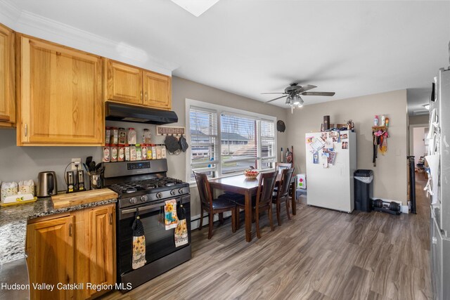 kitchen with under cabinet range hood, gas stove, freestanding refrigerator, a ceiling fan, and wood finished floors
