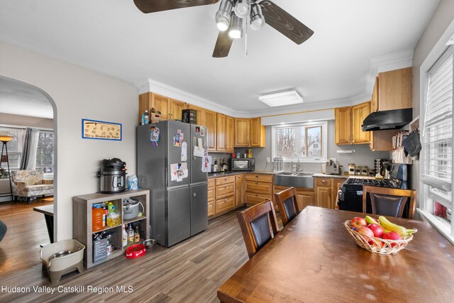 kitchen with a sink, a ceiling fan, under cabinet range hood, black appliances, and arched walkways