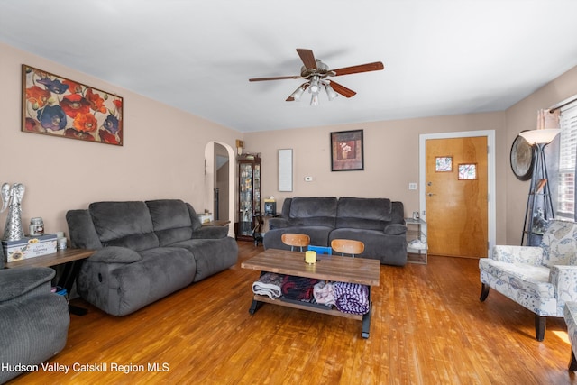 living room with arched walkways, ceiling fan, and wood finished floors
