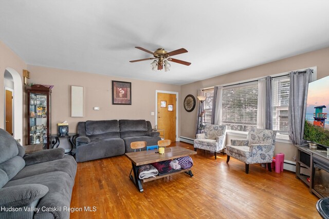 living room featuring wood finished floors, arched walkways, ceiling fan, and baseboard heating