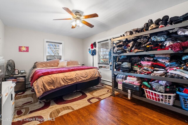 bedroom with a baseboard radiator, a ceiling fan, baseboard heating, and wood finished floors