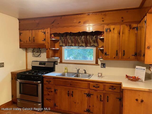 kitchen with decorative backsplash, stainless steel range with gas cooktop, and sink