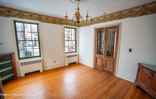 unfurnished dining area featuring an inviting chandelier, radiator, and light wood-type flooring