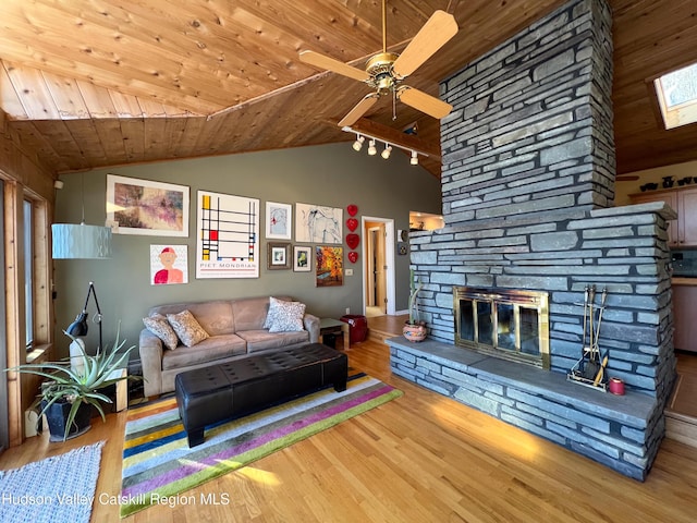 living room with vaulted ceiling with skylight, ceiling fan, wood ceiling, and hardwood / wood-style flooring