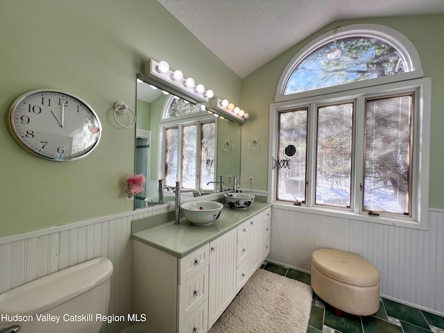 bathroom featuring tile patterned flooring, a textured ceiling, lofted ceiling, toilet, and vanity