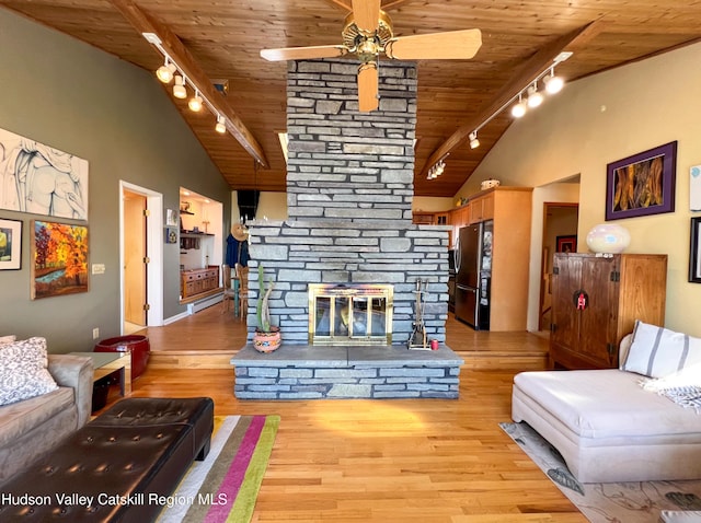 living room with light hardwood / wood-style floors, track lighting, a stone fireplace, and wood ceiling