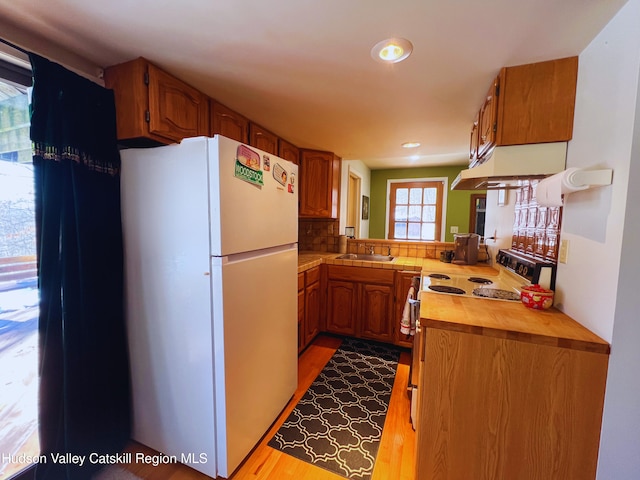 kitchen with sink, white refrigerator, light hardwood / wood-style floors, electric stove, and decorative backsplash