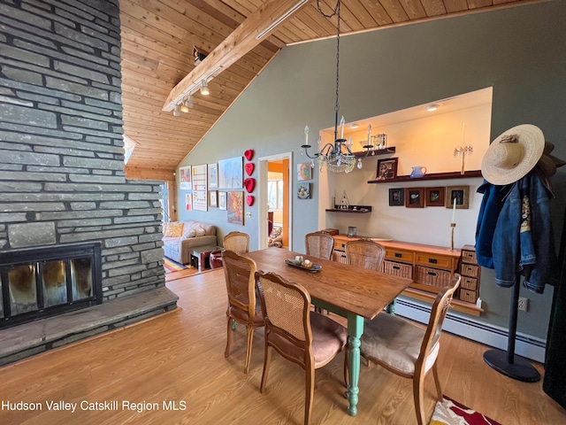 dining area featuring light wood-type flooring, a fireplace, wood ceiling, high vaulted ceiling, and beamed ceiling