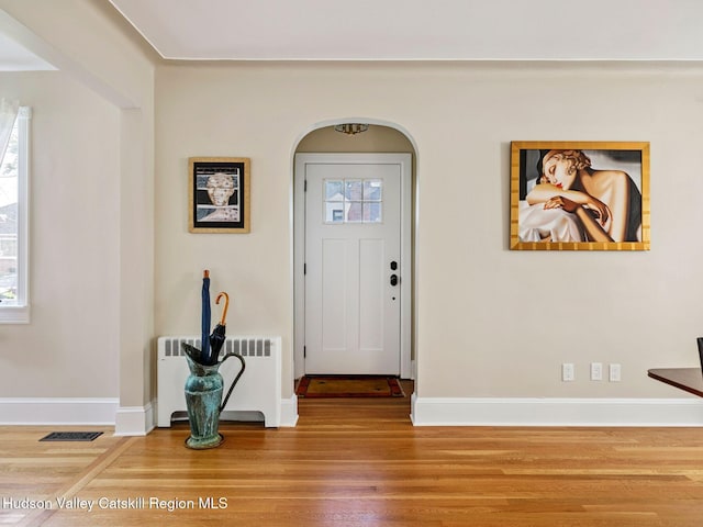 90 Emerson St, Kingston, NY 12401 - foyer entrance featuring radiator heating unit, wood finished floors, and arched walkways