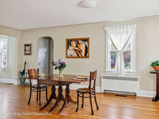 90 Emerson St, Kingston, NY 12401 - dining space featuring arched walkways, radiator heating unit, and light wood-style flooring