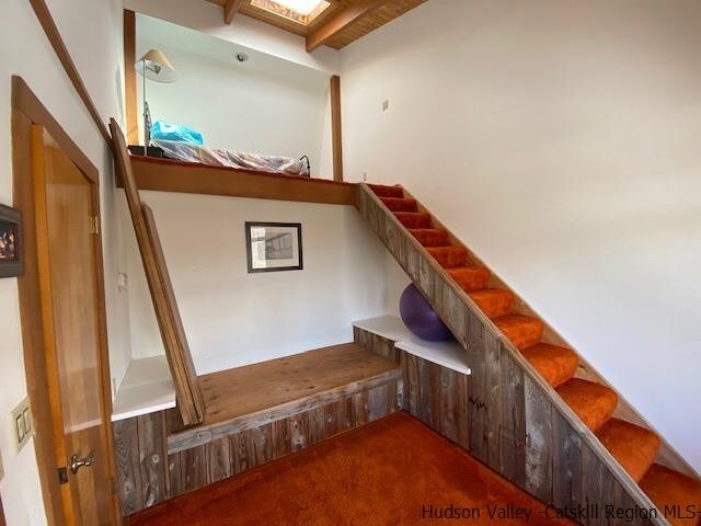 staircase with carpet and beam ceiling