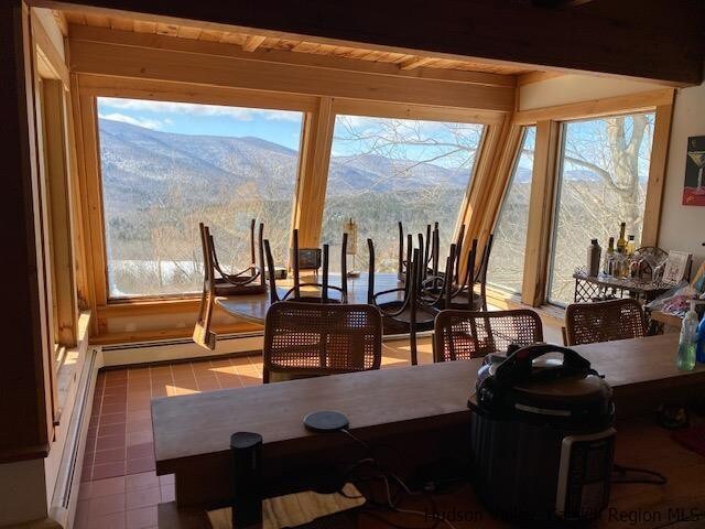 dining space featuring a mountain view, beam ceiling, wood ceiling, and a baseboard radiator