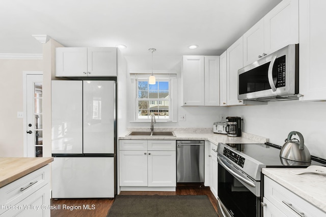 kitchen featuring stainless steel appliances, dark wood-type flooring, sink, decorative light fixtures, and white cabinets