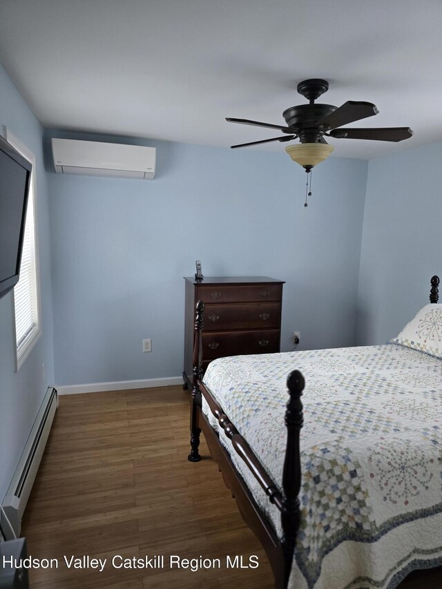 280 Continental Rd, Napanoch, NY 12489 - bedroom with a wall mounted AC, baseboard heating, wood finished floors, baseboards, and ceiling fan