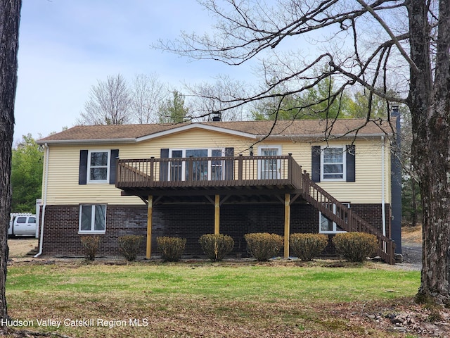 rear view of property with a deck, a chimney, a lawn, stairway, and brick siding