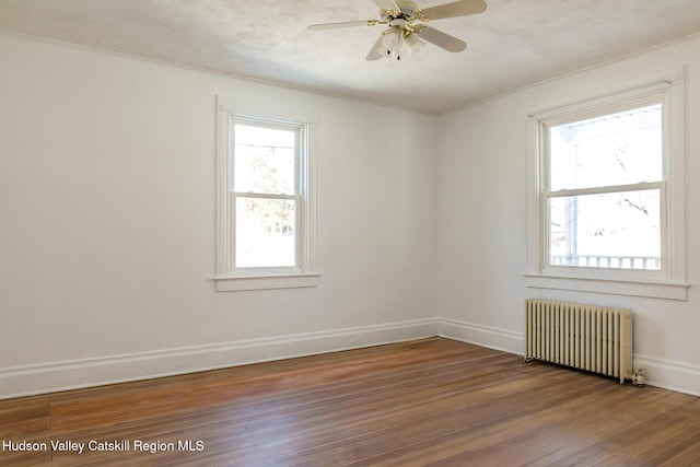 empty room with dark hardwood / wood-style flooring, radiator, and ceiling fan