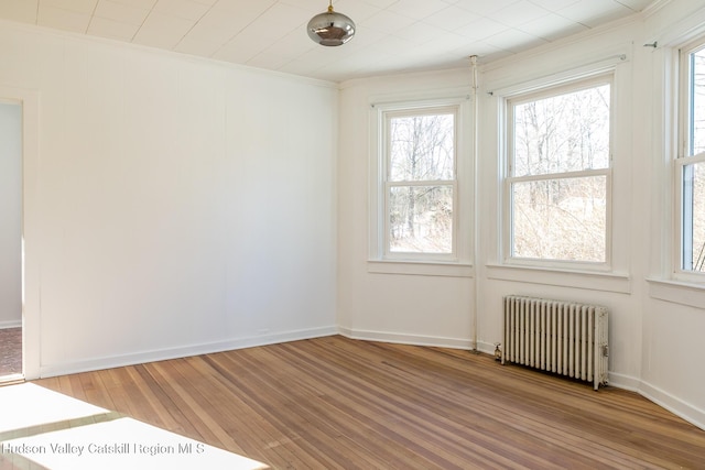 unfurnished room featuring radiator heating unit, ornamental molding, and wood-type flooring