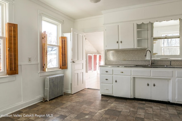 kitchen with a healthy amount of sunlight, radiator, sink, and white cabinets