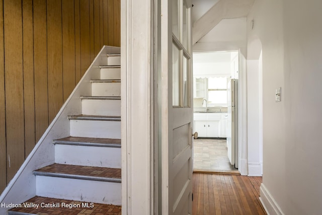 staircase with sink, hardwood / wood-style flooring, and wood walls