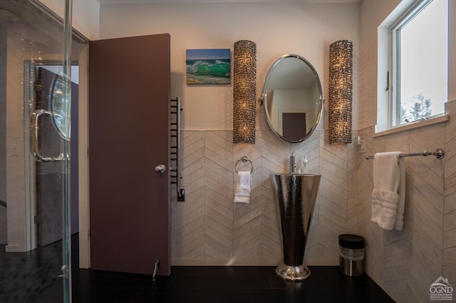  - bathroom with tile walls, wainscoting, and a shower with shower door