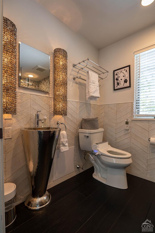  - bathroom featuring tile walls, toilet, and wainscoting