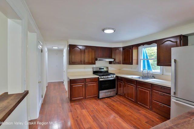 kitchen featuring stainless steel gas stove, white refrigerator, sink, and dark wood-type flooring