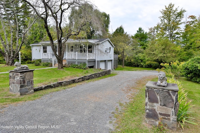 view of front of house featuring covered porch, a front yard, and a garage