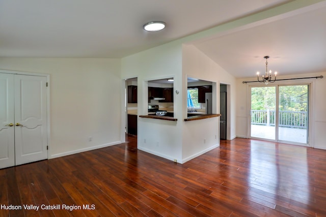 kitchen with a notable chandelier, dark wood-type flooring, appliances with stainless steel finishes, and vaulted ceiling