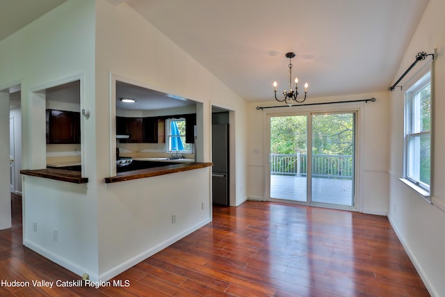 kitchen with lofted ceiling, dark brown cabinets, dark hardwood / wood-style floors, and a notable chandelier