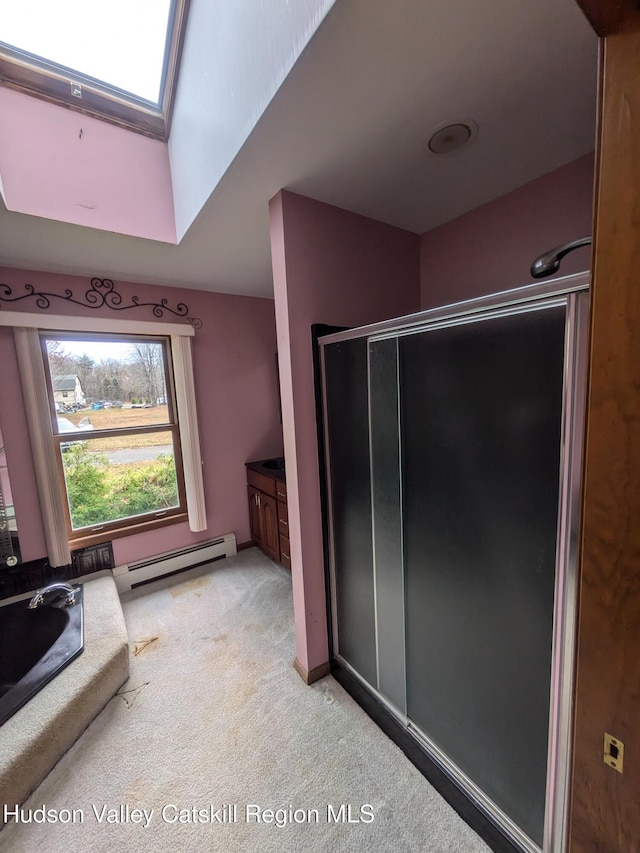 bathroom with baseboard heating, a skylight, a shower with door, and vanity