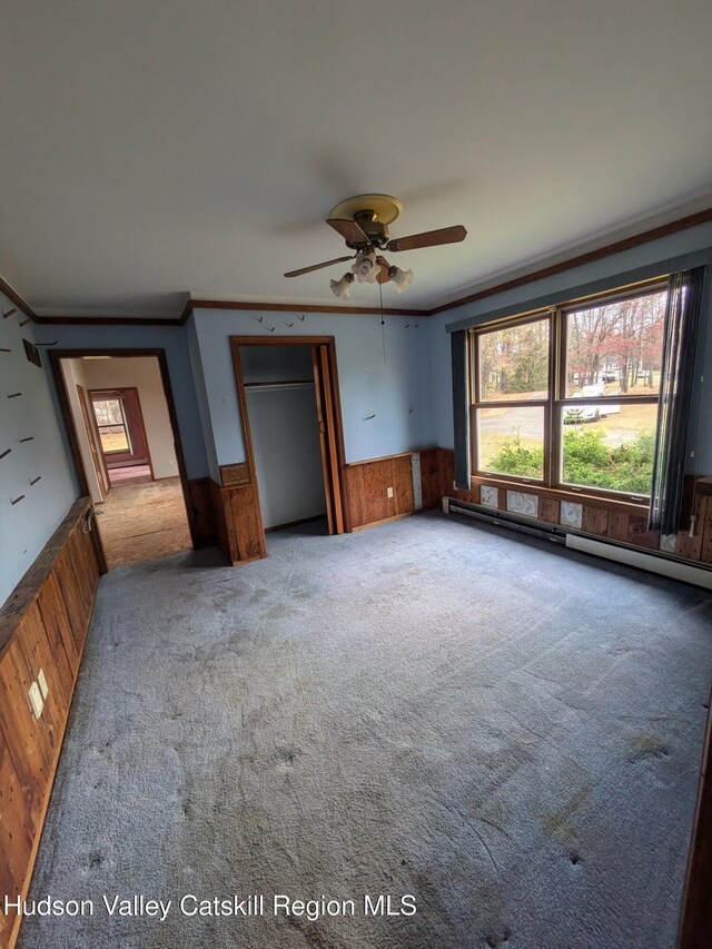 interior space featuring ornamental molding, carpet floors, and wooden walls