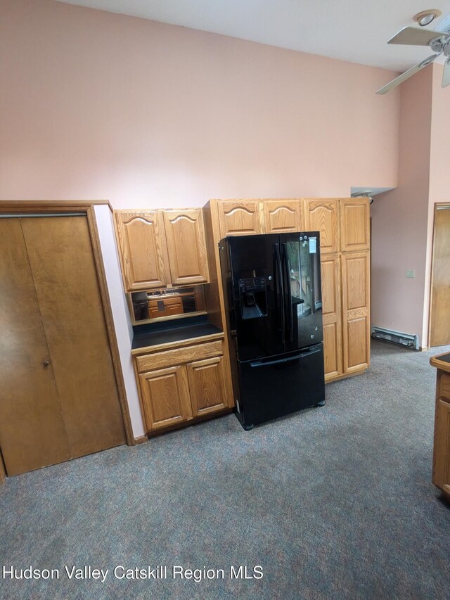 kitchen with black fridge, ceiling fan, dark carpet, and a baseboard radiator