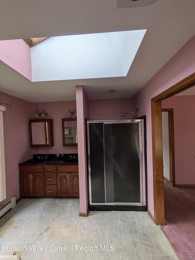 bathroom with vanity, a skylight, a baseboard radiator, and an enclosed shower