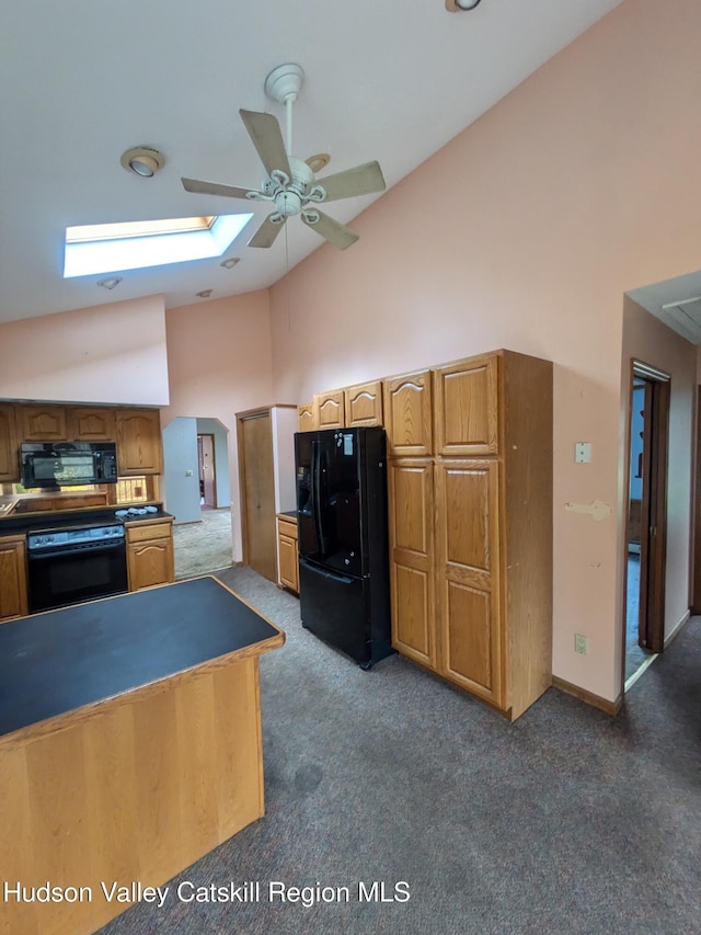 kitchen with a skylight, ceiling fan, black appliances, dark colored carpet, and high vaulted ceiling