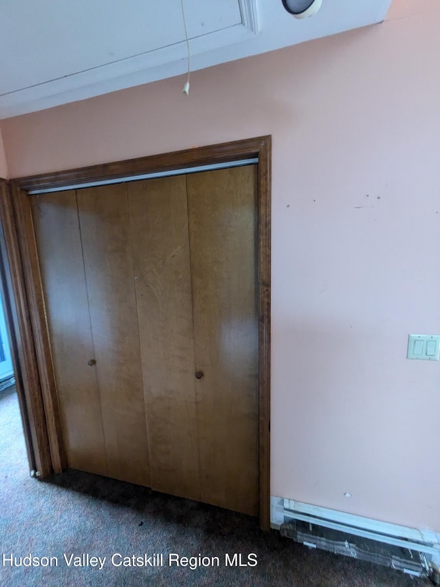 unfurnished bedroom featuring carpet, a baseboard radiator, and a closet