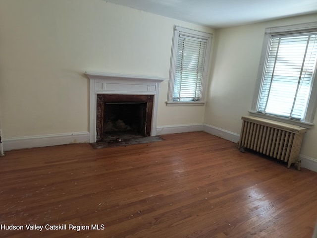 unfurnished living room featuring dark hardwood / wood-style flooring and radiator heating unit