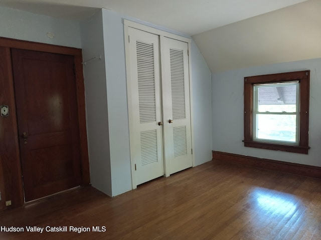 unfurnished bedroom featuring dark hardwood / wood-style floors, a closet, and vaulted ceiling