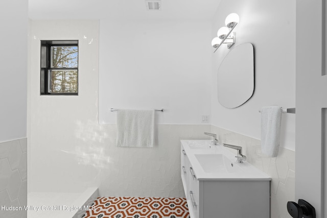 bathroom with vanity and tile walls