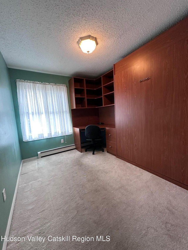 unfurnished office featuring a baseboard radiator, a textured ceiling, and light carpet