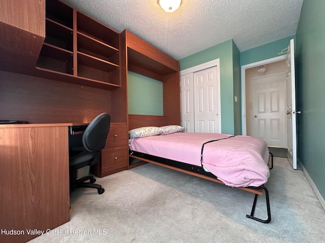 bedroom featuring a closet, light colored carpet, and a textured ceiling