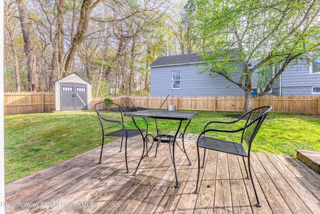 wooden terrace with a fenced backyard, an outbuilding, a storage shed, and a lawn