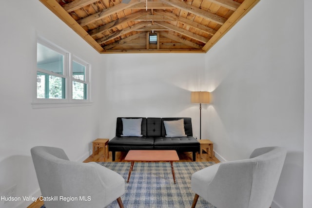 living area featuring wood ceiling, vaulted ceiling with beams, and baseboards