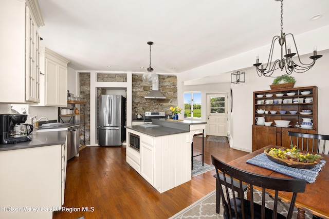 kitchen with dark wood-type flooring, hanging light fixtures, a notable chandelier, a kitchen island, and stainless steel appliances