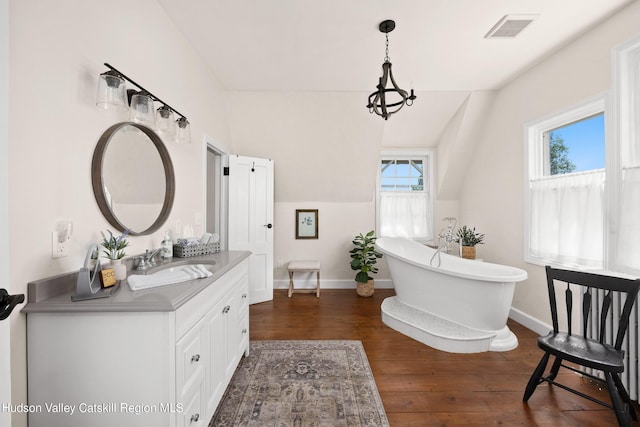 bathroom with hardwood / wood-style floors, vanity, a bathing tub, and lofted ceiling