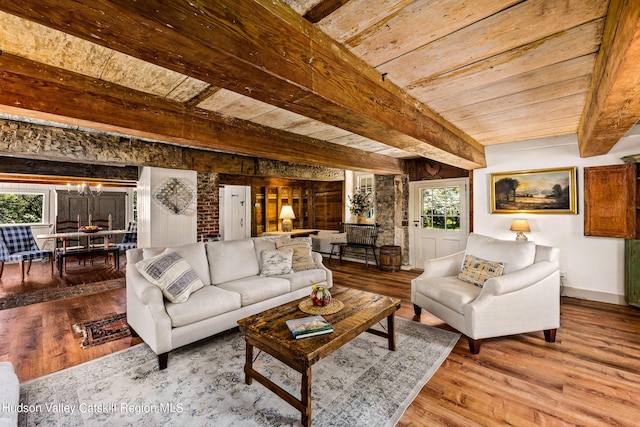 living room with beamed ceiling, a notable chandelier, a healthy amount of sunlight, and hardwood / wood-style flooring