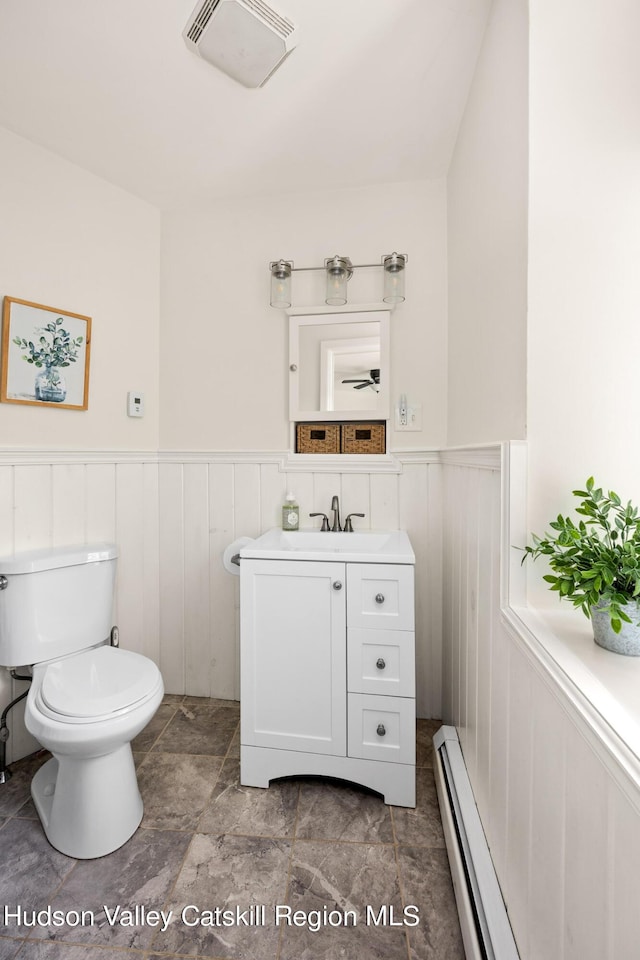 bathroom featuring vanity, a baseboard heating unit, and toilet