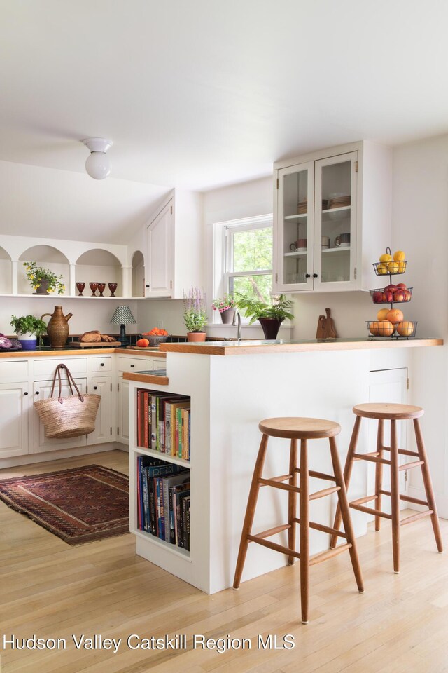72 Old Queechy Rd, Canaan, NY 12029 - kitchen with open shelves, a kitchen breakfast bar, light wood-style flooring, glass insert cabinets, and white cabinetry