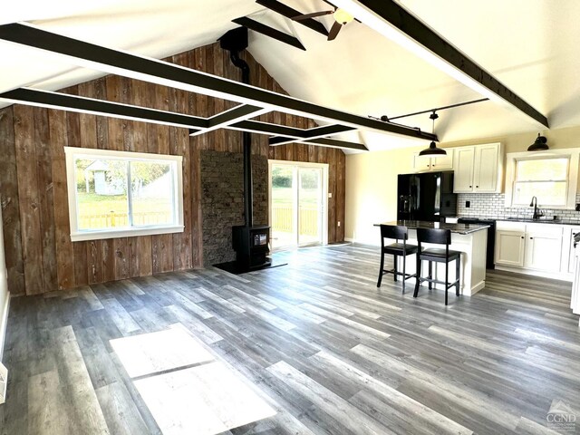 369 Newry Ln, Greenville, NY 12083 - living area with wooden walls, a wood stove, healthy amount of natural light, wood finished floors, and a ceiling fan