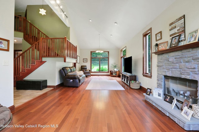 374 Linderman Ave, Kingston, NY 12401 - living room with stairs, high vaulted ceiling, wood finished floors, a stone fireplace, and a chandelier