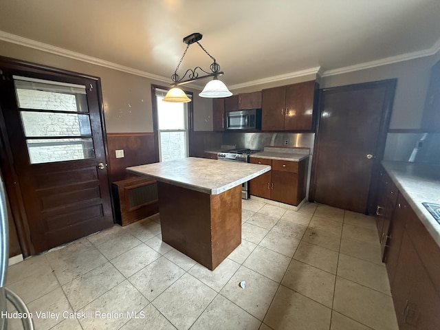 kitchen with a center island, crown molding, light countertops, wainscoting, and stainless steel appliances